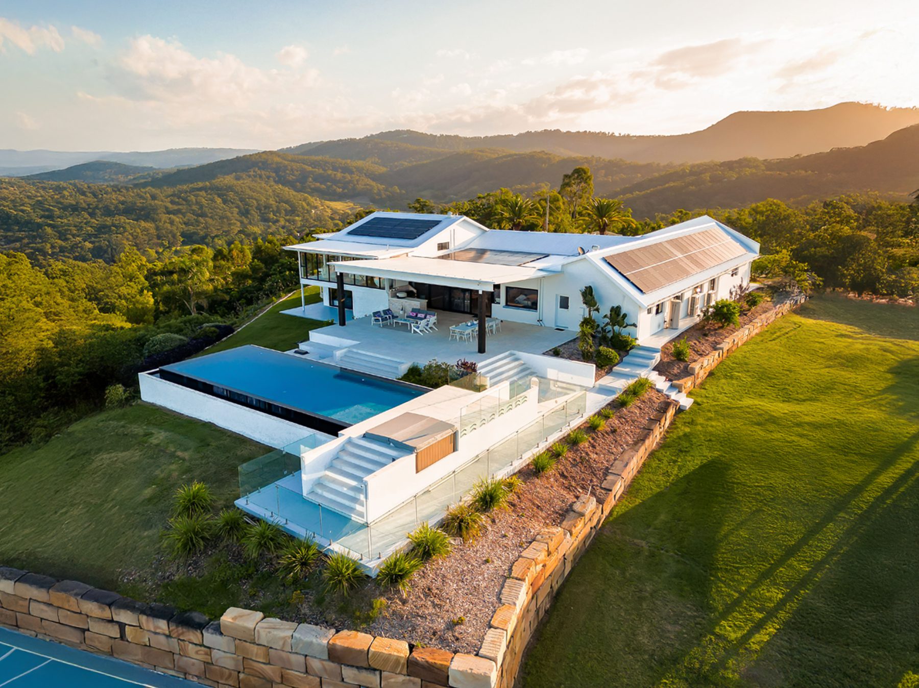 Aerial drone image of a hillside home with pool